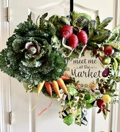 Explore the "Meet Me at the Market" vegetable wreath, a perfect addition to any kitchen. This wreath boasts a verdant greenery and mesh base, embellished with a sizable artificial cabbage, radish, carrots, lemons, olives, and a variety of fruits. The arrangement is enhanced with a ribbon bow featuring a vegetable pattern and a metal sign proclaiming "Meet Me at the Market," all nestled among extra greenery. Each wreath, swag, or door hanger is distinct; no two pieces are the same, except when sp Vegetable Wreath, Fruit Wreaths, Assorted Fruits, Wreath Swag, Fruit Wreath, Outdoor Display, Spring Wreaths, Variety Of Fruits, Housewarming Present