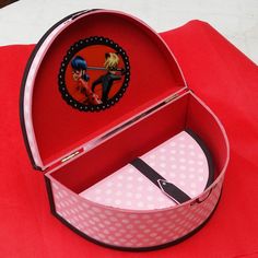 an open red box on top of a red cloth covered table with polka dot paper