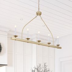 a chandelier hanging from the ceiling in a kitchen with white walls and cabinets