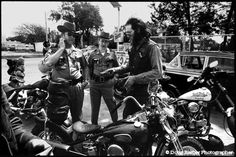 black and white photograph of men in uniform standing next to parked motorcyclists