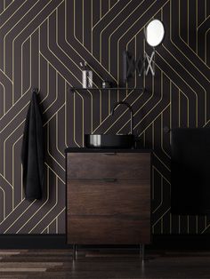 a black and gold geometric wallpaper with a wooden cabinet in the corner next to it