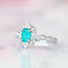 Gorgeous Vintage Inspired Neon Paraiba Tourmaline Ring Made of Solid Sterling Silver, Rhodium Plated (S925) Accented with Simulated Diamonds Center Stone: Paraiba Tourmaline Gemstone Creation: Lab-Created Stone Cut: Oval Color: Turquoise Gem size: 6.0 x 4.0 mm Carat Weight: 0.43 (approx.) Gemstone Origin: Brazil Can be made in solid gold and customized to a different gemstone. Please contact us if you have special requests. Handling time: 1-2 business days Free domestic shipping. Usually takes 2 Classic Turquoise Rings For Wedding, Turquoise Emerald-cut Gemstone Ring, Turquoise Emerald Cut Gemstone Ring, Turquoise Gemstone Rings With Emerald Cut, Emerald Cut Turquoise Gemstone Ring, Oval Turquoise Topaz Ring For Wedding, Elegant Turquoise Ring With Halo Setting For Anniversary, Turquoise Oval Emerald Ring For Anniversary, Turquoise Emerald Ring For Anniversary