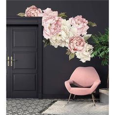 a pink chair sitting in front of a black wall with flowers on it and an open door