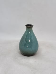 a green vase sitting on top of a white table