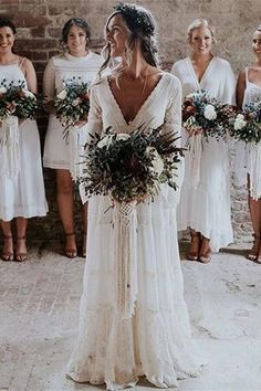 a bride and her bridals standing in front of a brick wall holding bouquets