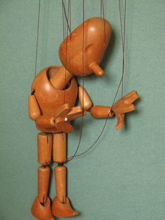 a wooden toy hanging from strings in the shape of a man with an arm and foot