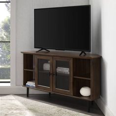 a flat screen tv sitting on top of a wooden entertainment center next to a window