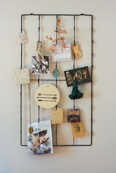 a wall hanging with pictures and magnets attached to the metal bars that hold them