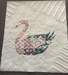 a close up of a quilt with a bird on it's back and an embroidered design in the middle