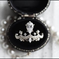 an open black velvet box with a white diamond ring in it's center piece