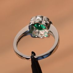 It is a lab emerald ring. The main stone is 7mm*7mm round cut, weight about 1.30 carats. The basic metal is sterling silver and plated with rhodium. To change the metal to a solid gold (white/rose) or platinum is also available, please ask for a quotation if you want. You can also go to my shop Home for more elegant rings: https://www.etsy.com/shop/godjewelry?ref=hdr_shop_menu More emerald rings: https://www.etsy.com/shop/godjewelry?ref=hdr_shop_menu§ion_id=20709240 Customization is always welco Emerald Crystal Ring With Round Cut And Prong Setting, White Gold Emerald Crystal Ring, Emerald Promise Ring With Center Stone, Green Emerald Ring With Center Stone, Green Diamond Ring In Sterling Silver For May Birthstone, Emerald Promise Ring With Halo Setting, Promise Emerald Ring With Halo Setting, Green Sterling Silver Diamond Ring For May Birthstone, White Gold Emerald Ring For Promise With Center Stone