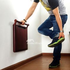 a man standing next to a wall with his foot on the side of a cabinet