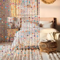 a bed room with a neatly made bed next to a window covered in beaded curtains