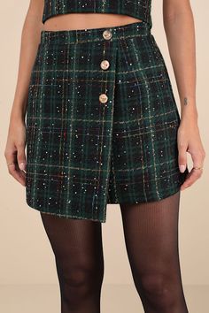 Step out for the day knowing you'll be the cutest around in the Lulus Adorably Posh Dark Green Multi Plaid Tweed Faux-Wrap Mini Skirt! Woven, green and black plaid tweed, with multi-colored stitching, sparking tinsel-like gold threading, and little sequins throughout, shapes this chic mini skirt with a high-waisted fit. The figure-flattering A-line silhouette features an overlapped design that lends a faux-wrap effect, decorated with embossed gold button details. Exposed zipper at back. Pair with the matching top for a complete look! Fit: This garment fits true to size. Length: Mid-thigh. Size medium measures 17" from waist to hem. Waist: Fitted - very fitted at natural waist. Hip: Loosely Fitted. Fabric: Fabric has no stretch. Lined. Shell: 100% Polyester. Lining: 100% Cotton. Hand wash C Green Tweed Skirt Outfit, Green Plaid Skirt Outfit, Tweed Skirt Outfit, Green Plaid Skirt, Plaid Skirt Outfit, Green Tweed, Button Skirt, Wrap Mini Skirt, Tweed Skirt