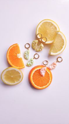 oranges and lemon slices cut in half on a white surface with two gold rings