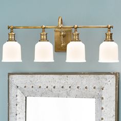 a bathroom vanity with three lights and a mirror on the wall next to it in front of a blue wall