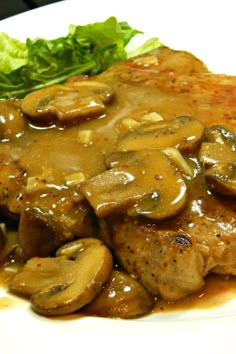 a white plate topped with meat covered in mushroom gravy