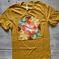 Oh my...such a happy, colorful quilt block tee!100% combed and ring-spun cotton (heather colors are 99% combed and ring-spun cotton, 1% polyester), NOTE this tee is slightly different from the triblend tees in the shop. The sizing and fit is the same but this tee is 100% cotton and a tad heavier in weight and with a little less stretch than the triblend.Contemporary/modern unisex fit - true to size CareWe use the latest direct-to-garment (DTG) printing technology and high-quality inks that won't Printed Garments, Quilt Shirt, Colorful Quilt, Colorful Bouquet, Colorful Quilts, Barn Quilt, Garment Labels, Dtg Printing, Patchwork Quilt