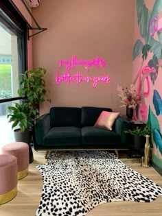 a living room with pink walls and black couches in front of a large window