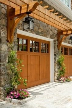 two wooden garage doors with flowers in the planters on either side and an attached light fixture above them