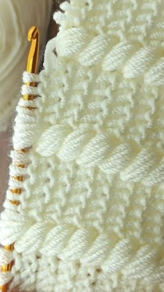 a close up view of a white crochet blanket with yellow pins on it