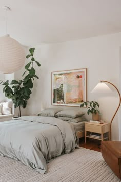 a bedroom with a bed, chair and plant in it