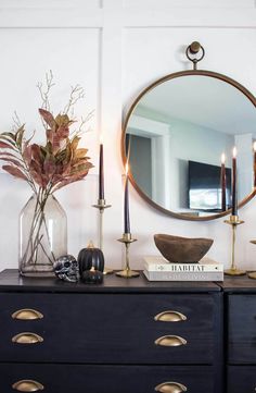 a black dresser topped with a mirror and candles