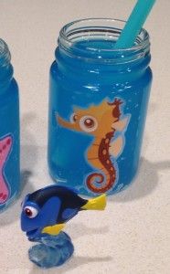 two jars with toothbrushes in them sitting next to a toy sea horse and fish