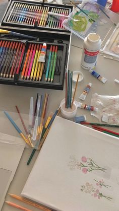 art supplies are sitting on a table with watercolors and pencils in them