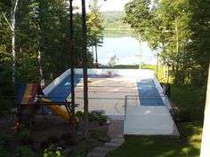 an outdoor basketball court surrounded by trees and water