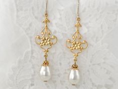 Delightfully eclectic and with an Art Nouveau flair, these earrings are delicate gold floral filigree are embellished with white Swarovski crystal pear shaped pearl dangles. They are the perfect wedding event or elopement earrings. They make for fabulous gifts for the bride, mother of the bride, or bridesmaids. Finished with 14K Gold-Filled ear wires, these are the perfect earring for sensitive ears, and for wowing the eyes. *Handcrafted design *Delicate silver finish over filigree *Crystal pear Vintage Dangle Flower Earrings For Wedding, White Dangle Bridal Earrings With Intricate Design, Delicate Brass Wedding Earrings, White Bridal Dangle Earrings With Intricate Design, White Bridal Earrings With Intricate Dangle Design, Vintage Gold Pearl Earrings For Wedding, Pierced Brass Bridal Earrings For Wedding, Delicate Gold Chandelier Earrings With Pearl Drop, Pierced Brass Flower Earrings For Wedding