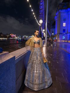 This lehenga set features antique silver sequin embroidery in a geometric pattern. The blouse shows crystal tassels at the waist. Embroidered dupatta also shows crystal tassels. The outfit can be paired with (an optional) antique gold cape jacket with matching embroidery. The jacket has heavy beaded tassels.From Seema Gujral's For the love of London collection. DELIVERY TIMEPlease allow 8-12 weeks for your outfit to arrive. FABRIC DETAILSNet Professional cleaning only. Silver Hand Embellished Sharara For Festive Occasions, Festive Silver Hand Embellished Dupatta, Festive Silver Hand Embellished Sharara, Festive Hand Embellished Silver Dupatta, Festive Silver Hand-embellished Dupatta, Festive Silver Embellished Set, Festive Embellished Silver Sets, Silver Anarkali Style Hand Embellished Sharara, Silver Hand Embellished Anarkali Dupatta