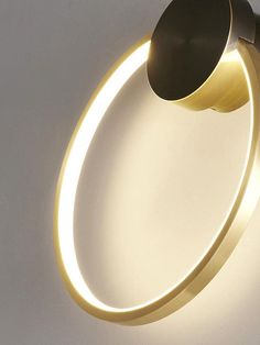 an illuminated circular light fixture on a white wall with a black and gold ring around it