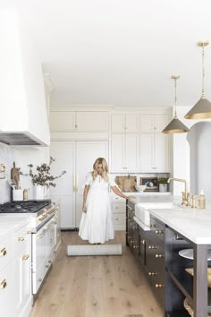 a woman in a white dress is walking through the kitchen