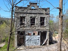 an old abandoned building with graffiti on it's windows and door is surrounded by trees