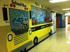 the school bus is painted yellow and has many pictures on it's front wall