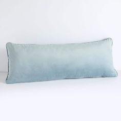 a blue pillow sitting on top of a white bed