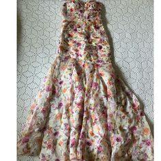 a dress that is laying on top of a bed sheet with flowers all over it