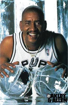 a basketball player is holding two clear water jugs in his hands and smiling at the camera