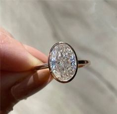 a close up of a person's hand holding a ring with a diamond in it