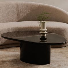 a black table with a potted plant on it in front of a beige couch