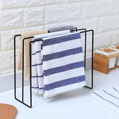 three towels are hanging on a rack in front of a white brick wall