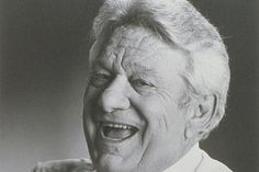 an old man laughing while wearing a suit and tie