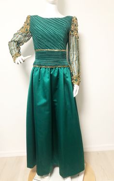 This is a stunning gown from Lillie Rubin and George F. Couture. The dress is a gorgeous shade of green accented with gold sequins and bugle beads at the waistline. The sleeves are sheer and hand beaded with jewels and sequins. You will certainly feel like a princess wearing this one. Long zipper in back, lined tulle skirt for fullness. Size tag 6, check measurements carefully, no stretch. Made in USA. Measurements taken with dress laying flat and doubled where appropriate. In order to determine Green Formal Ball Gown With Fitted Bodice, Formal Green Ball Gown With Fitted Bodice, Green Ball Gown With Fitted Bodice For Formal Occasions, Green Long Sleeve Gown With Sequins, Green Evening Dress With Sheer Bodice, Fitted Green Sequin Evening Dress, Sheer Sleeves Fitted Bodice Evening Dress For Banquet, Fitted Bodice Evening Dress With Sheer Sleeves For Banquets, Elegant Green Gown With Sheer Bodice