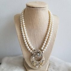 This is a vintage statement necklace from the 1950's-1960's. The necklace is made from two white pearl tone bead strands. The pendant is also the clasp of the necklace and is a white pearl tone and AB crystal statement piece. The back is a gold tone metal with the Japan signature. The necklace has a few areas of wear on the back from age. The necklace is in great condition.Measurements:Strand Length: 17" | Pendant Length: 2.25" | Pendant Width: 1.75"Unless otherwise stated all vintage items are Vintage Round Bead Necklace For Anniversary, Vintage Round Beads Necklace For Anniversary, Vintage Pearl White Necklaces With Pearl Charm, Vintage White Double Strand Beaded Necklaces, Vintage White Double Strand Beaded Necklace, Vintage Pearl Pendant Necklace For Party, Vintage Cream Pearl Drop Jewelry, White Vintage Necklaces For Vintage Events, Vintage White Necklace For Party