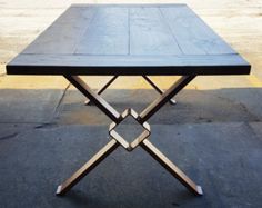 a wooden table sitting on top of a parking lot next to a sidewalk with no one around it