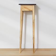 a small wooden table sitting on top of a hard wood floor next to a white wall