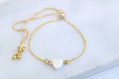 "This beautiful bracelet features a tiny Mother of pearl carved heart on a dainty 18k gold filled chain. A lovely bracelet that you can wear anywhere and with any outfit. It also makes a perfect gift for bridesmaid, best friends or just for yourself. BRACELET SIZE A perfect adjustable chain bracelet. Easy to put on, just slide the gold bead for best fit. 9\" long (Fits most wrist) GEMSTONE * Mother of pearl carved heart * Heart measures approx. 6 mm * Due to the one-of-a-kind nature of the stone Adjustable Delicate Heart Bracelet, Delicate Adjustable Bracelets For Valentine's Day, Delicate Adjustable Bracelet For Valentine's Day, Delicate Adjustable Heart Bracelet For Everyday, Adjustable Delicate Heart Bracelet For Everyday, Gold Charm Bracelet With Adjustable Length As Gift, Gold Charm Bracelet With Adjustable Length, Delicate Heart-shaped Bracelets With Adjustable Chain, Dainty Heart Bracelet With Adjustable Chain For Wedding