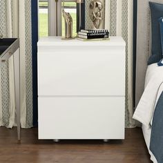 a white nightstand sitting next to a bed in a room with blue and white curtains