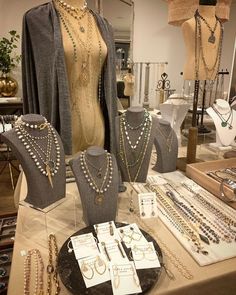 a table topped with lots of necklaces and jewelry next to mannequins